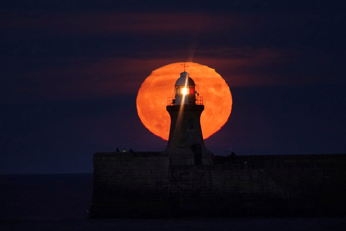 In this Sept. 20, 2021 file photo, a Harvest Moon rises over South Shields lighthouse on the north east coast of England.